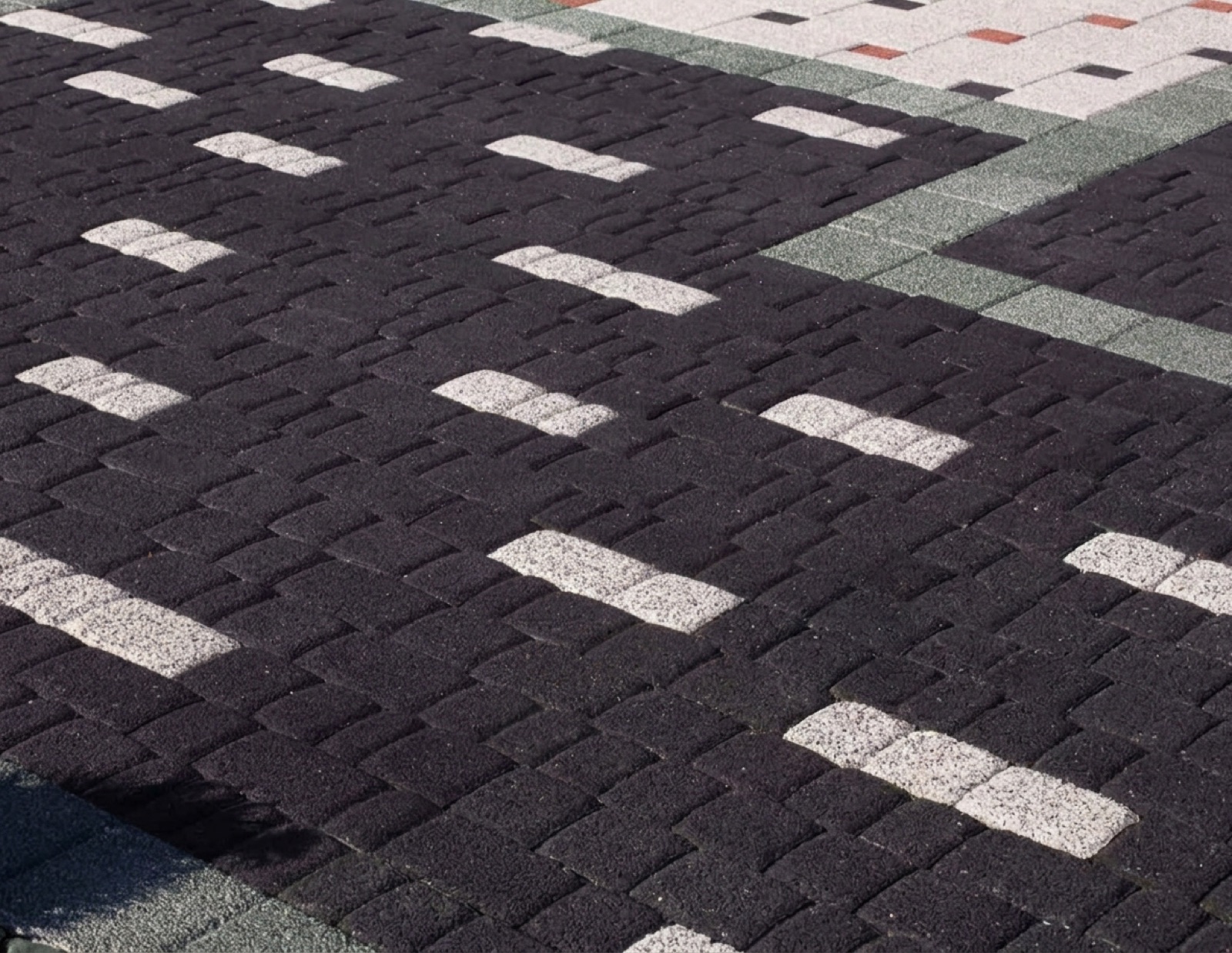 Dark ANTIK cobble paving with lighter stone inserts scattered across the surface
