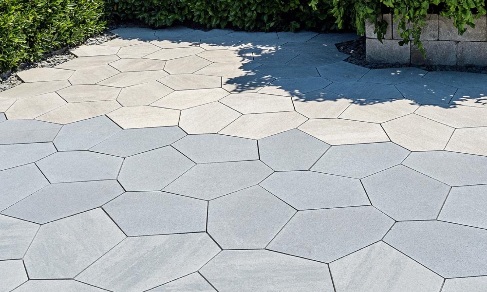PENTA five-sided pavers in light and blue-grey tones across a shaded courtyard